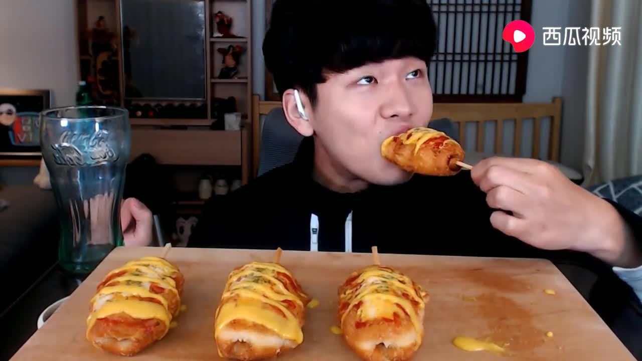韩国吃货小哥,吃香肠面包串,配上酱料,大口大口的吃,太馋人了