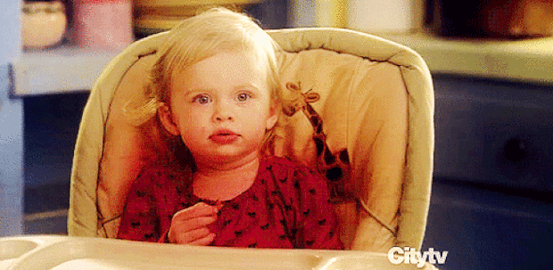 黑色爱心红色衣服黄头发俩岁国外小女孩坐在一个有长颈鹿的掎子gif