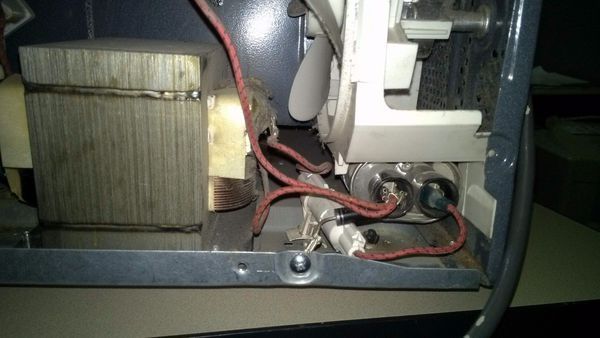 微波炉内部图,左侧金属块状物是变压器,右侧下方带两个电极的物体是